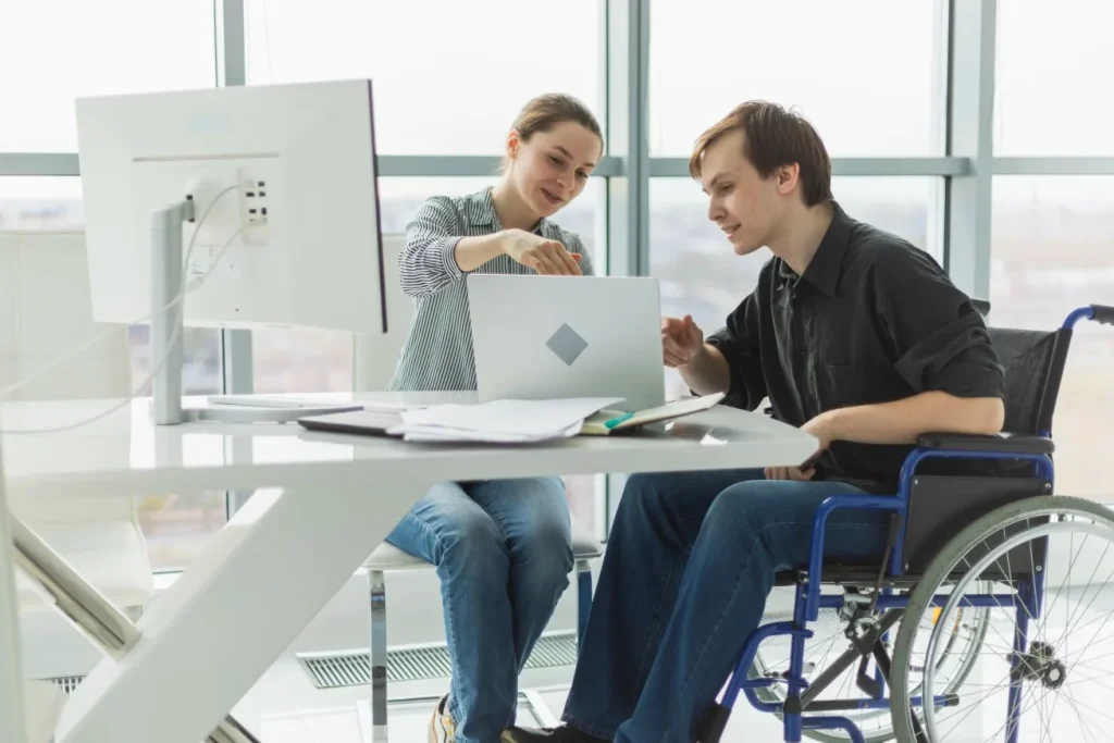A support provider is helping a young man with life tasks on his computer