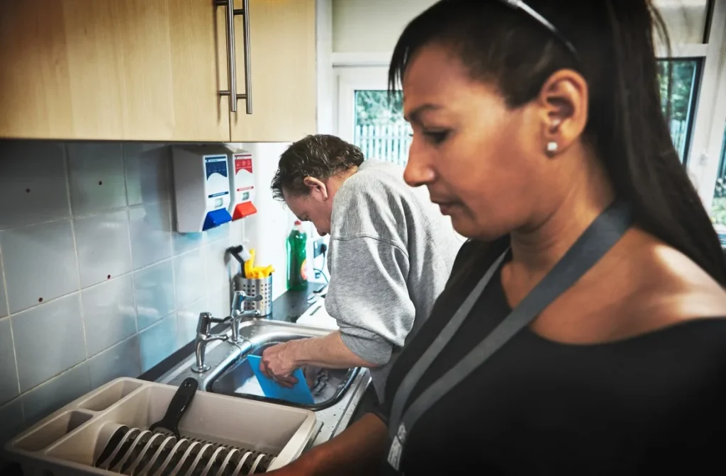 A man and woman are both cleaning dishes together in a kitchen