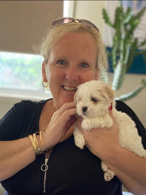 A photo of out founder carol holding her dog and smiling